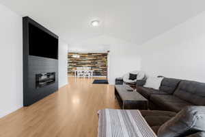 Living room featuring lofted ceiling, light wood-type flooring, baseboards, and a fireplace