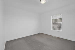 Unfurnished room featuring baseboards and dark colored carpet