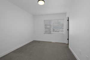 Spare room with dark colored carpet and baseboards