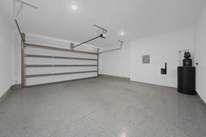 Garage featuring electric panel, a garage door opener, and recessed lighting