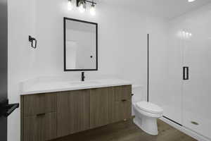 Full bath featuring vanity, wood finished floors, toilet, and a shower stall