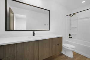 Full bathroom featuring toilet, vanity, wood finished floors, and shower / bath combination