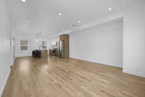 Unfurnished living room with light wood-style flooring, recessed lighting, a sink, and baseboards