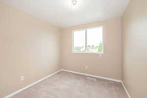 Spare room with light carpet and baseboards