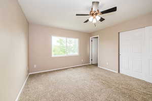 Unfurnished bedroom featuring carpet flooring, a closet, baseboards, and a ceiling fan