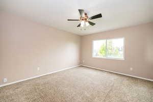 Empty room with carpet flooring, ceiling fan, and baseboards