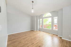 Unfurnished room with light wood-style floors, vaulted ceiling, and baseboards
