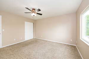 Spare room featuring carpet, healthy amount of natural light, ceiling fan, and baseboards