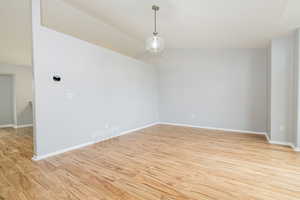 Unfurnished room with light wood-style floors, lofted ceiling, and baseboards