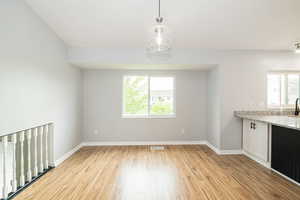 Unfurnished dining area with healthy amount of natural light, light wood-style floors, and baseboards