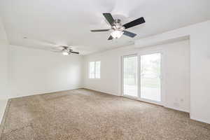 Carpeted empty room featuring ceiling fan and baseboards