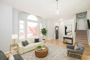 Living area featuring stairs, light wood finished floors, and lofted ceilingVirtually Staged