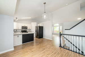 Kitchen with fridge with ice dispenser, stainless steel microwave, range with electric cooktop, a sink, and open floor plan