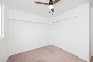 Unfurnished bedroom featuring carpet floors, a closet, baseboards, and ceiling fan