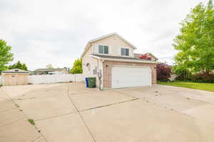 View of property exterior featuring concrete driveway, brick siding, and an attached garage