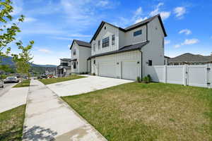 View of home's exterior featuring an attached garage, a gate, driveway, board and batten siding, and a standing seam roof