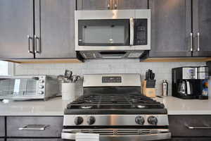 Kitchen with appliances with stainless steel finishes, light countertops, tasteful backsplash, and dark brown cabinetry