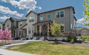 View of front of house featuring board and batten siding, a residential view, a front yard, and stone siding