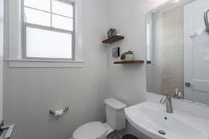 Bathroom with a sink, toilet, and healthy amount of natural light