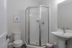 Bathroom featuring a shower stall, toilet, and a sink