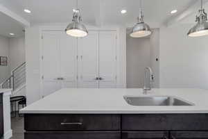 Kitchen with a sink, light countertops, recessed lighting, pendant lighting, and wooden ceiling with exposed beams