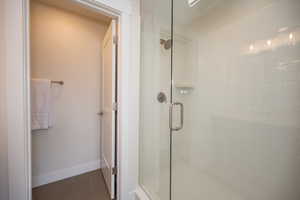 Bathroom with a stall shower, tile patterned flooring, and baseboards