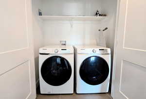 Washroom with washing machine and clothes dryer and light tile patterned flooring