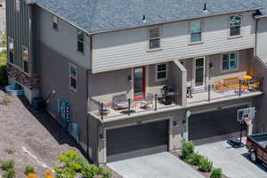 Back of house featuring an attached garage, roof with shingles, driveway, and stucco siding