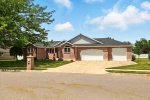 Ranch-style home featuring driveway, a front lawn, an attached garage, and brick siding