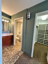 Bathroom with pocket door, toilet, vanity, and baseboards next to extra large walk in closet