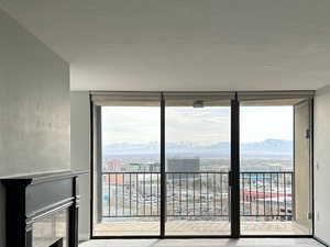 Unfurnished living room with carpet flooring, a fireplace, a wall of windows overlooking the city view