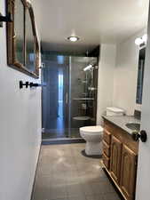 Bathroom featuring toilet, vanity, a shower stall, and a textured ceiling