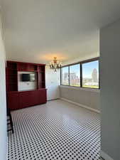 Unfurnished dining area featuring custom cabinetry, new paint and dimmable chandelier w/ black and white tile floor.