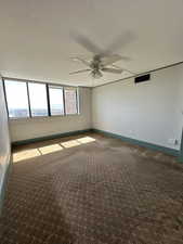 Carpeted empty room with ceiling fan and baseboards
