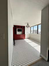 Unfurnished sunny dining room with a chandelier and baseboards