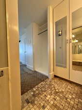Hallway in primary bedroom with  closet and mirrored storage, carpet floors