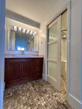 En-suite Full bathroom with ornamental molding, vanity, and a shower