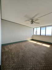 Carpeted spare room featuring ceiling fan and baseboards