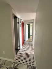 Hall with baseboards and a textured ceiling