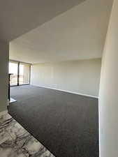 Carpeted empty room featuring baseboards and marble look tile flooring