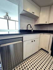 Kitchen featuring dishwasher, dark countertops, and tasteful backsplash
