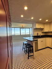 Kitchen featuring granite countertops, recessed lighting, a dimmable chandelier, a textured ceiling, and stainless steel dishwasher