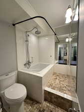 Full bathroom featuring tiled shower / bath, toilet, and a textured ceiling