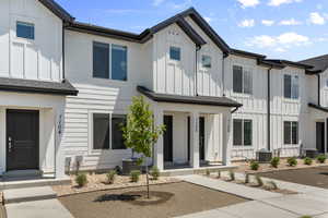 View of front facade featuring board and batten siding, covered porch, and cooling unit