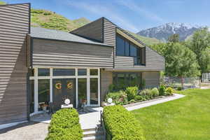 Back of property with a mountain view, french doors, and a lawn