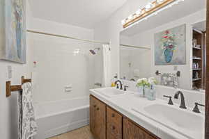 Full bath with shower / tub combo with curtain and double vanity