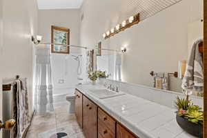 Bathroom with vanity, shower / tub combo with curtain, toilet, and tile patterned floors