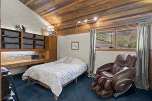 Carpeted bedroom featuring a textured wall, wood ceiling, and vaulted ceiling