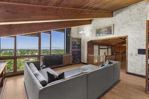 Living area featuring wood finished floors, wood ceiling with exposed beams, baseboards, and a chandelier