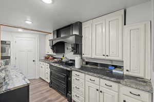 Kitchen with stainless steel double oven, white cabinets, a textured ceiling, light wood finished floors, and gas cooktop